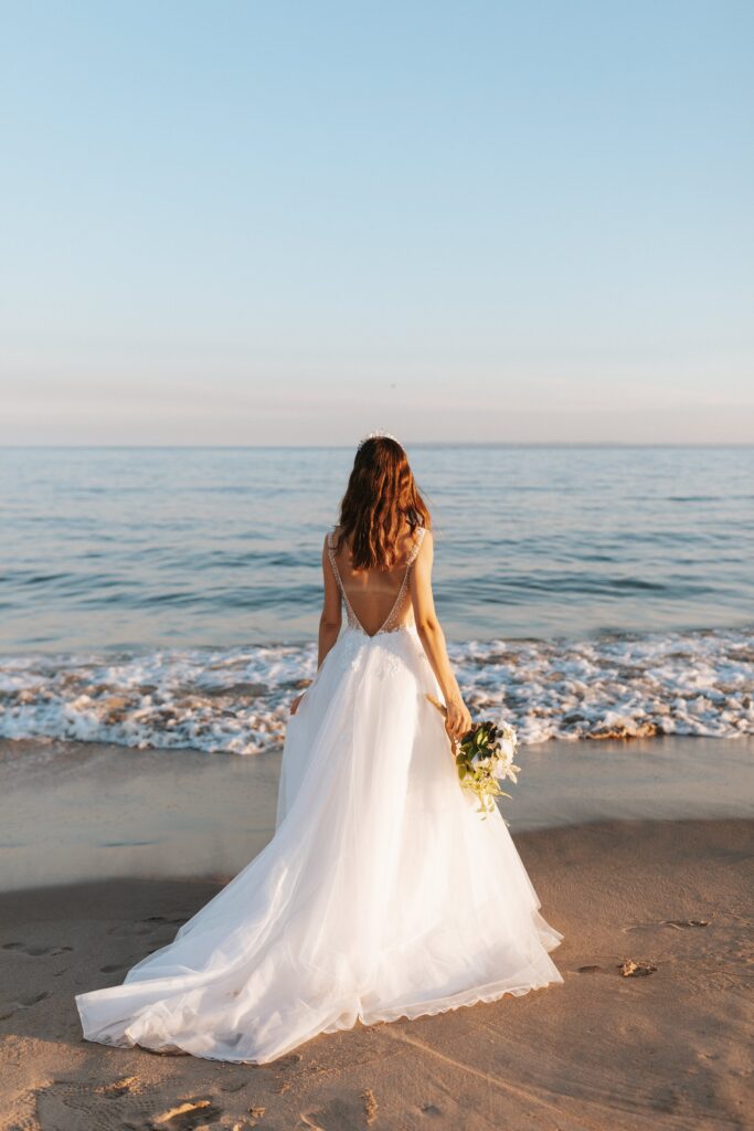 ウェディングドレスを着て海辺にたたずむ女性