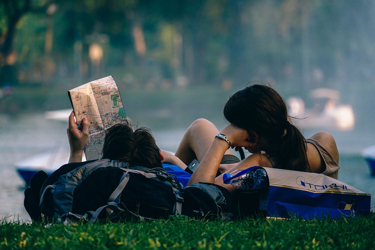芝生に寝転んで読書をする恋人同士